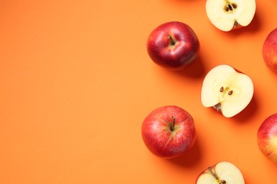 Photo of Whole and cut fresh red apples on orange background, flat lay. Space for text