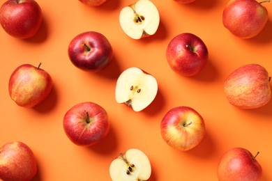 Photo of Whole and cut fresh red apples on orange background, flat lay