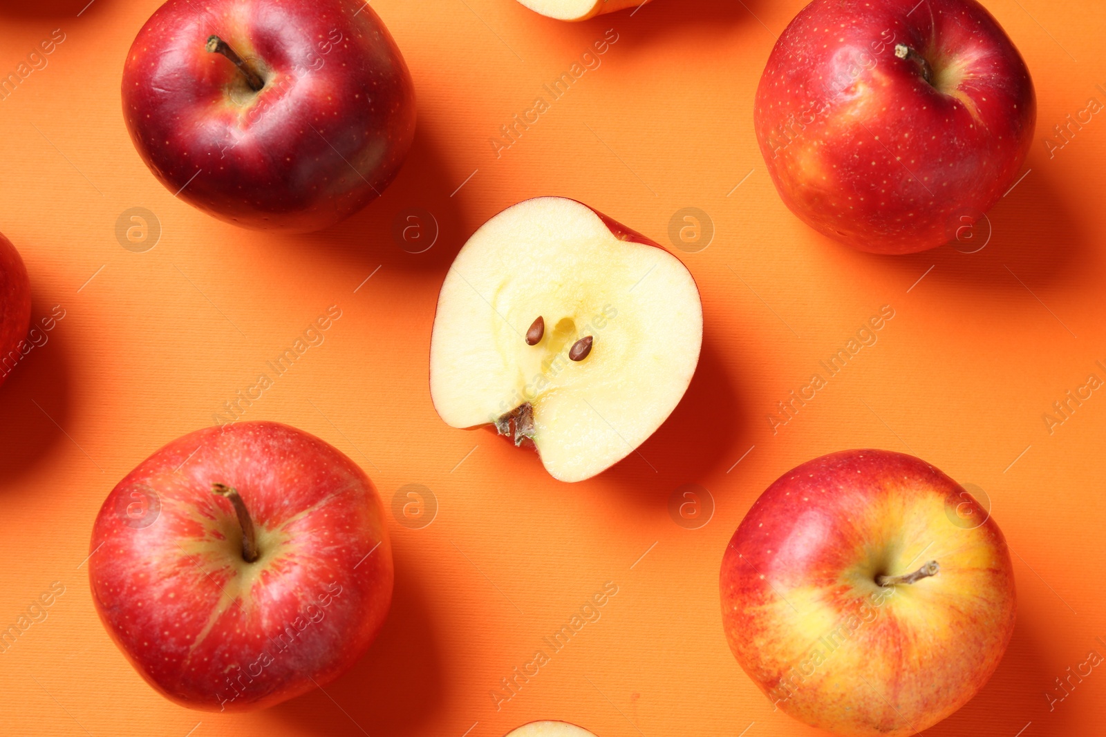 Photo of Whole and cut fresh red apples on orange background, flat lay