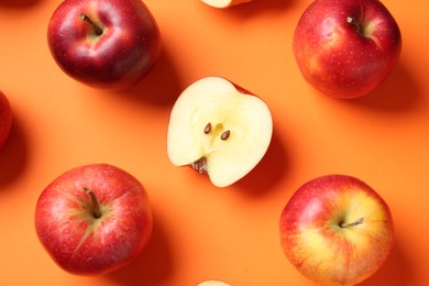 Photo of Whole and cut fresh red apples on orange background, flat lay