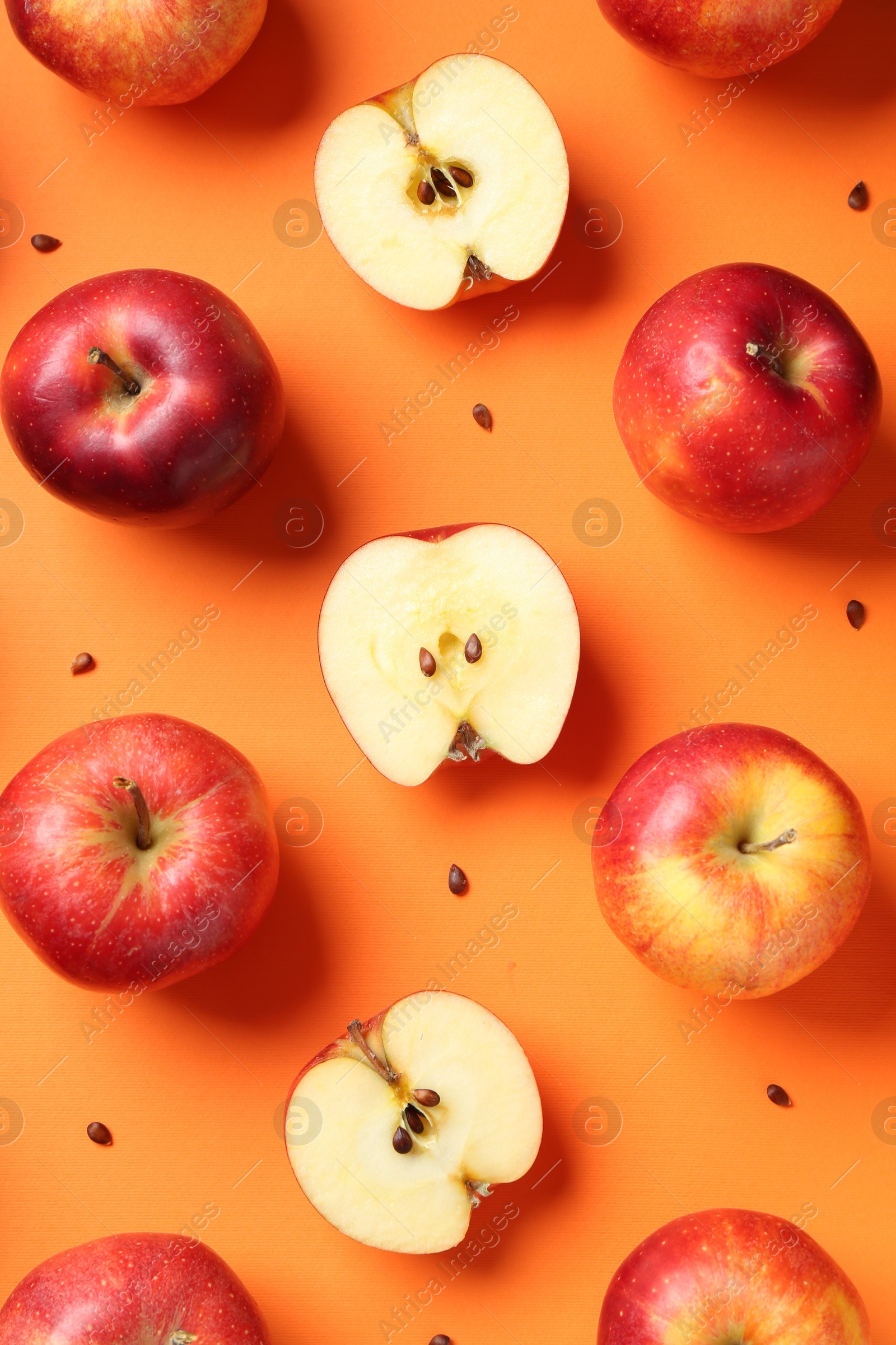 Photo of Fresh red apples and seeds on orange background, flat lay