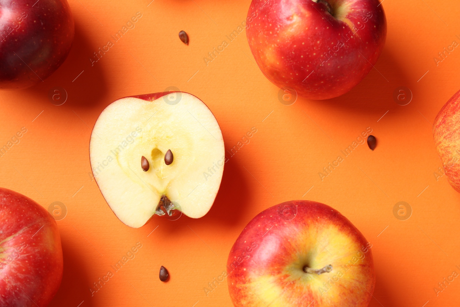 Photo of Fresh red apples and seeds on orange background, flat lay