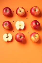 Fresh red apples and seeds on orange background, flat lay