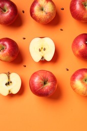 Photo of Fresh red apples and seeds on orange background, flat lay