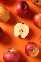 Photo of Whole and cut fresh red apples on orange background, flat lay