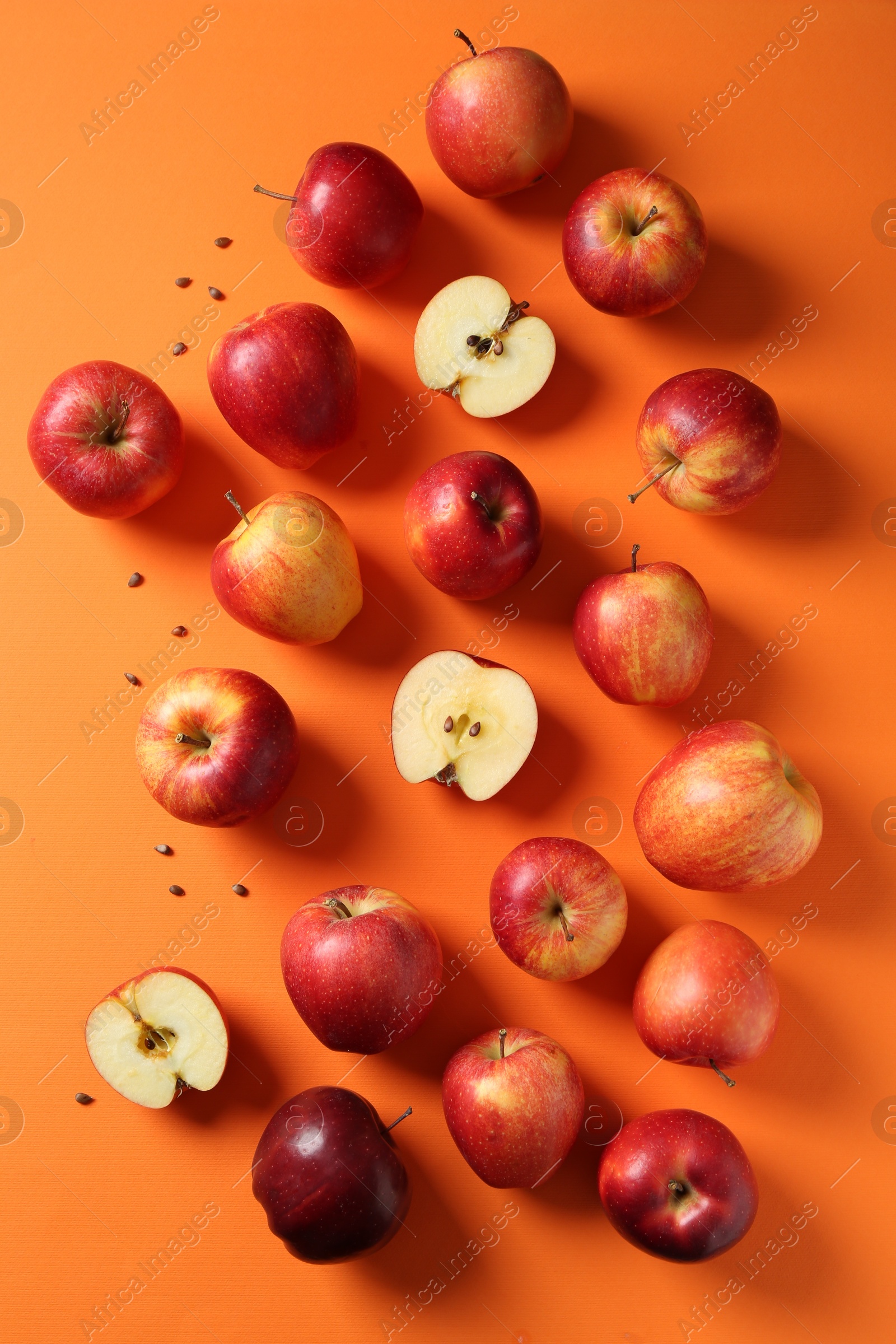 Photo of Fresh red apples and seeds on orange background, flat lay