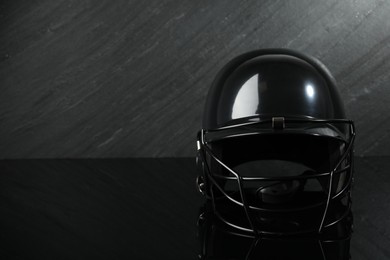 Black baseball helmet on dark gray background, space for text