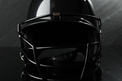 Photo of Black baseball helmet on dark gray background, closeup