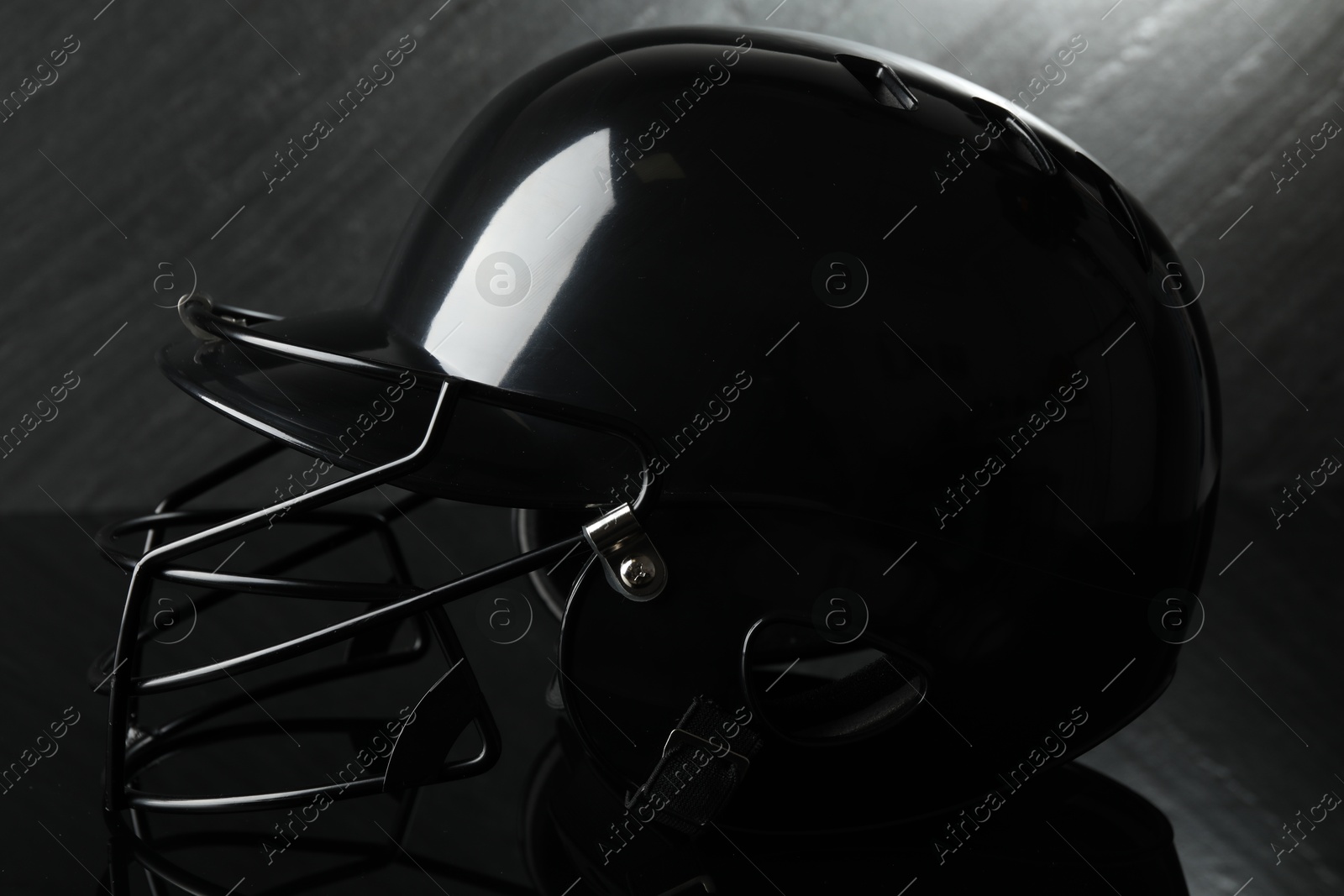 Photo of Black baseball helmet on dark gray background, closeup