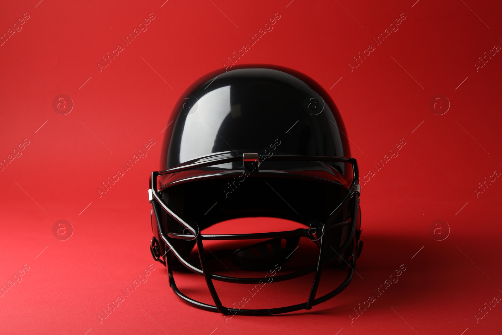 Photo of One black baseball helmet on red background