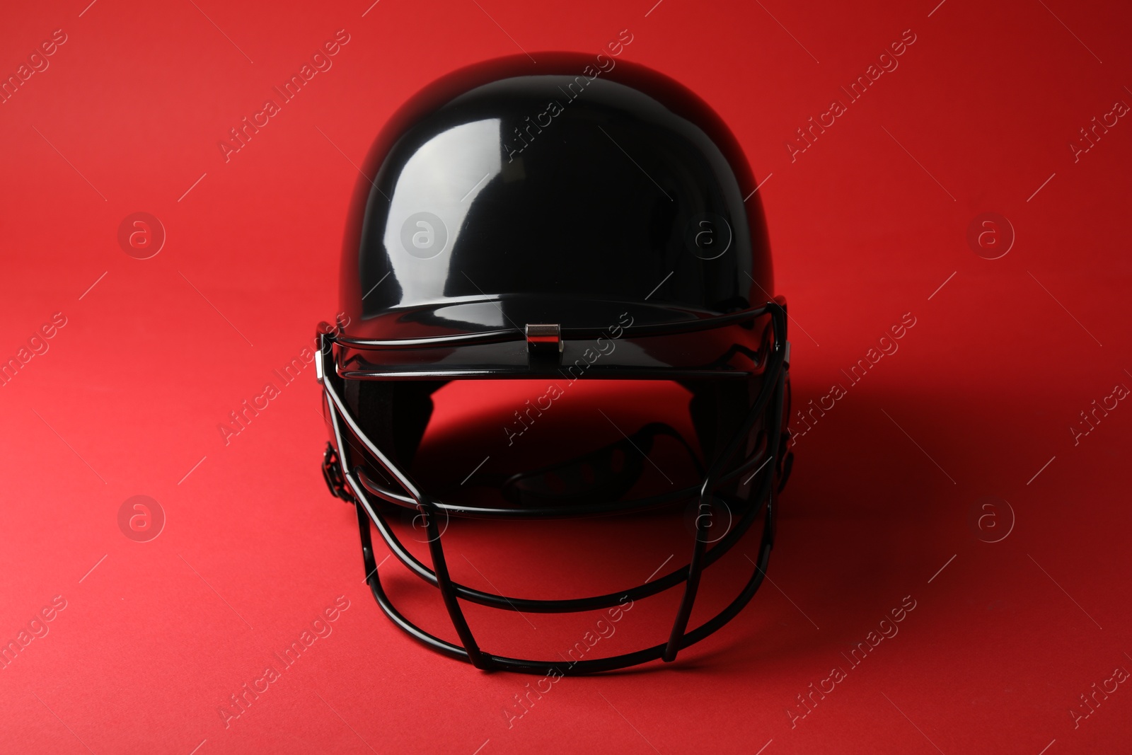 Photo of One black baseball helmet on red background