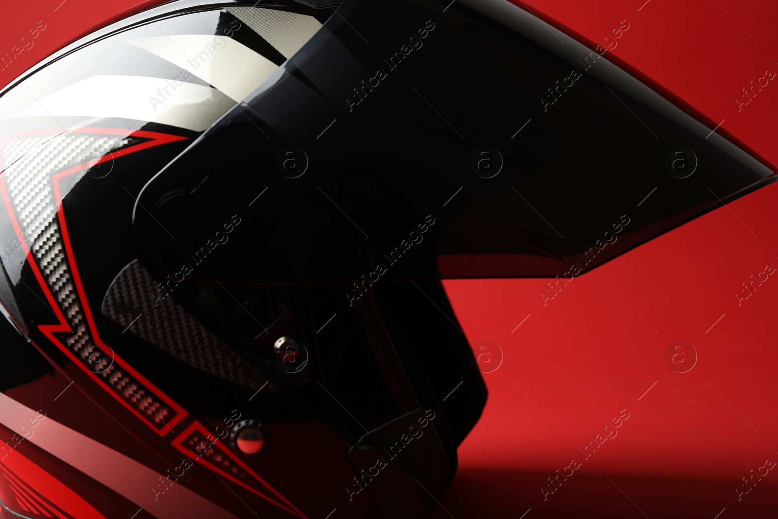 Photo of Modern motorcycle helmet with visor on red background, closeup