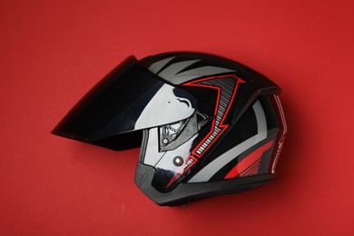 Photo of Modern motorcycle helmet with visor on red background, top view