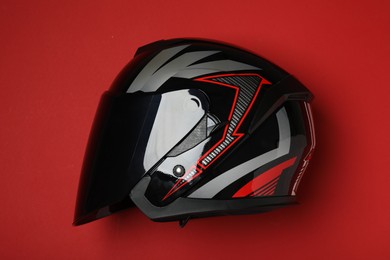 Photo of Modern motorcycle helmet with visor on red background, top view