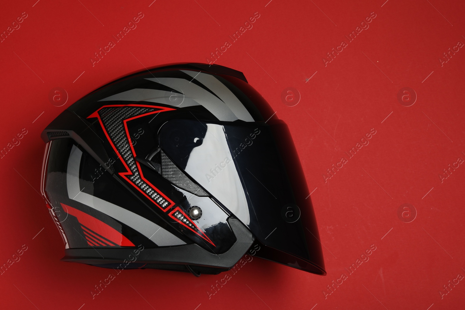 Photo of Modern motorcycle helmet with visor on red background, top view. Space for text