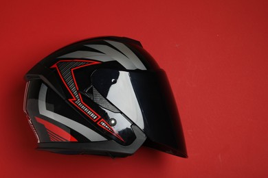 Modern motorcycle helmet with visor on red background, top view. Space for text