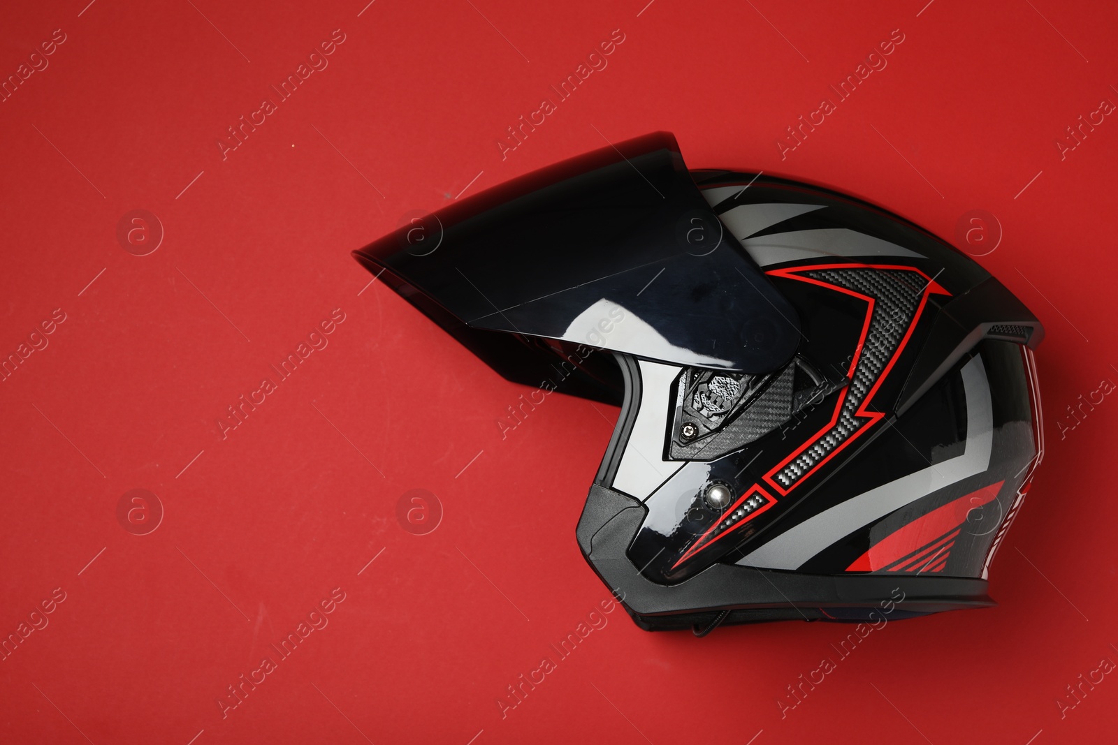 Photo of Modern motorcycle helmet with visor on red background, top view. Space for text