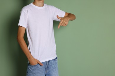 Photo of Teenage boy wearing white t-shirt on green background, closeup. Space for text