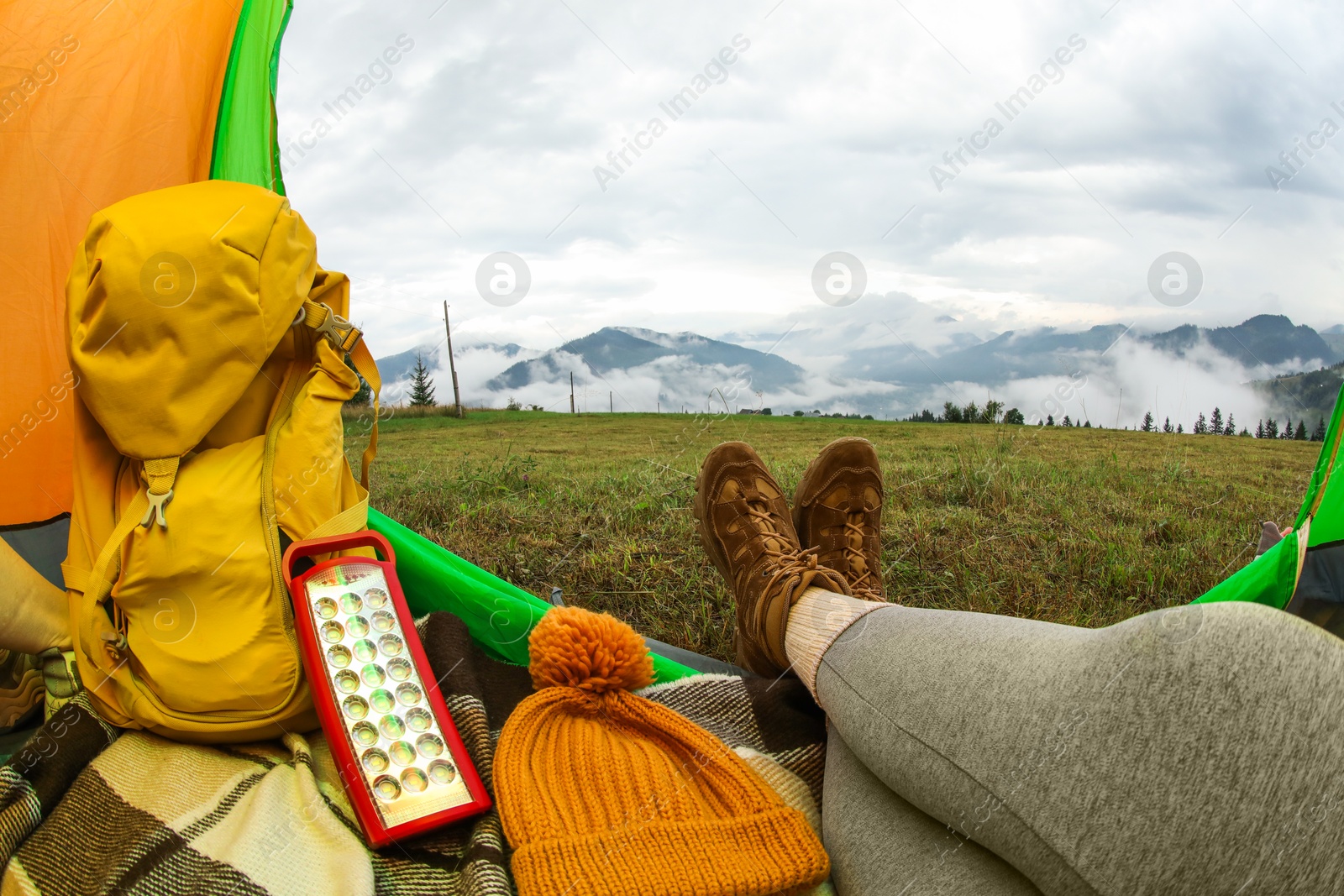 Photo of Woman wearing trekking shoes and lying in tent outdoors, closeup