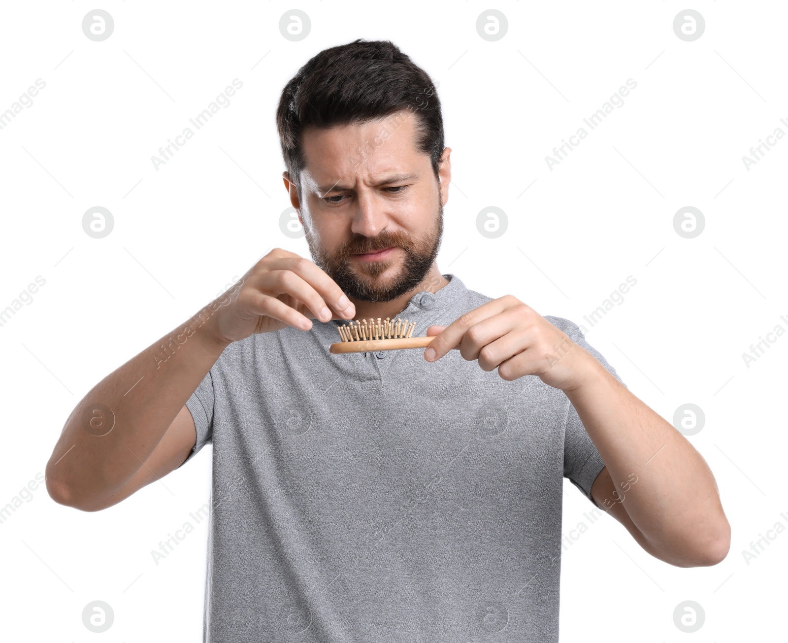 Photo of Sad man taking his lost hair from brush on white background. Alopecia problem