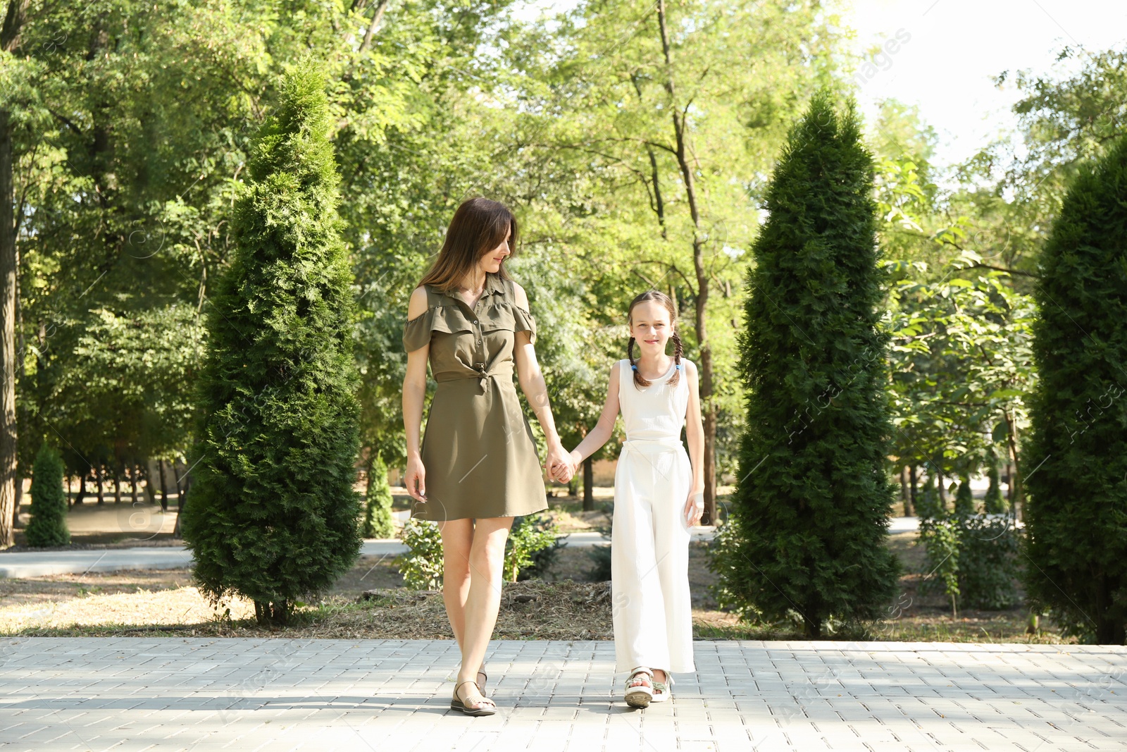 Photo of Mother and daughter holding hands while walking in park