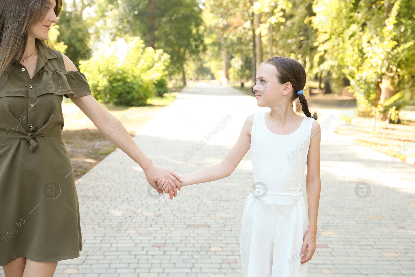 Photo of Little girl holding hands with mother in park