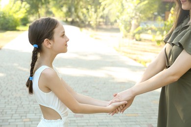 Little girl holding hands with mother in park, closeup