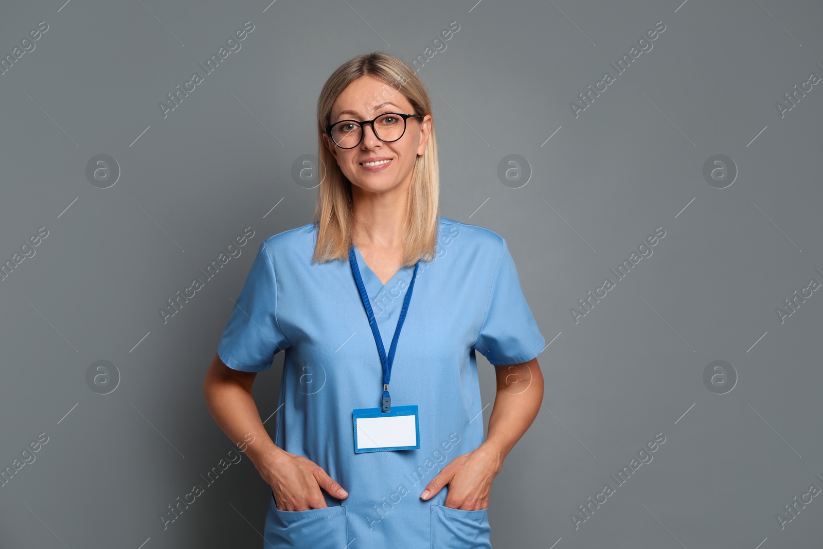 Photo of Nurse in medical uniform with badge on grey background