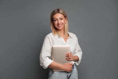 Beautiful woman with laptop on grey background