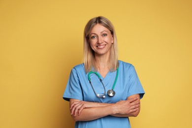 Portrait of nurse in medical uniform with stethoscope on yellow background