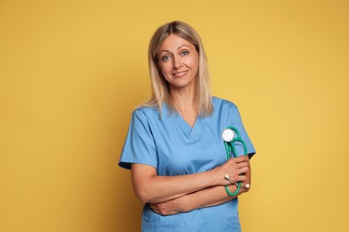 Photo of Portrait of nurse in medical uniform with stethoscope on yellow background