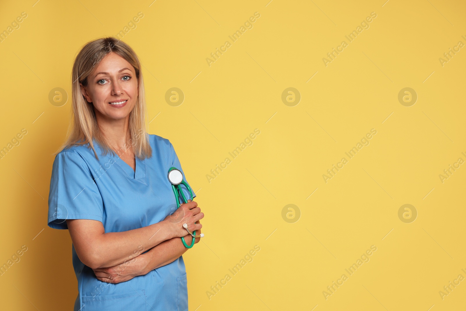 Photo of Portrait of nurse in medical uniform with stethoscope on yellow background, space for text