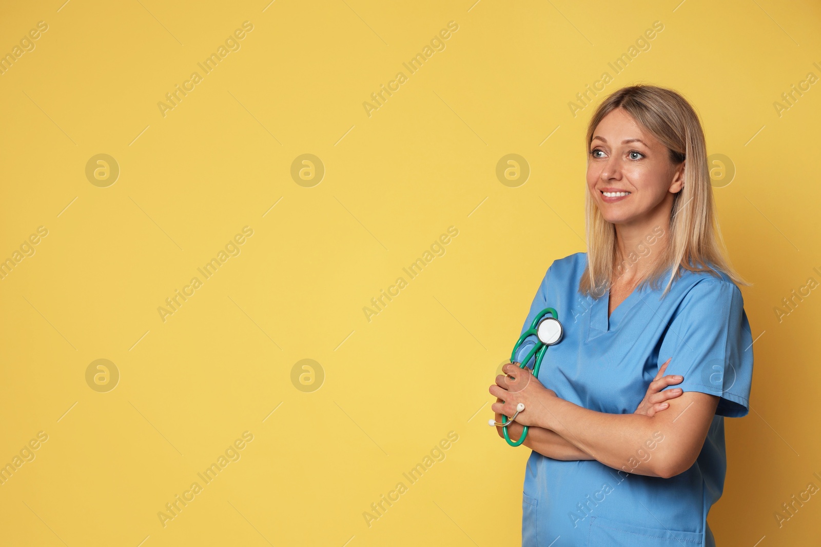 Photo of Portrait of nurse in medical uniform with stethoscope on yellow background, space for text