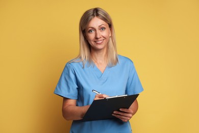 Photo of Portrait of nurse in medical uniform with clipboard on yellow background