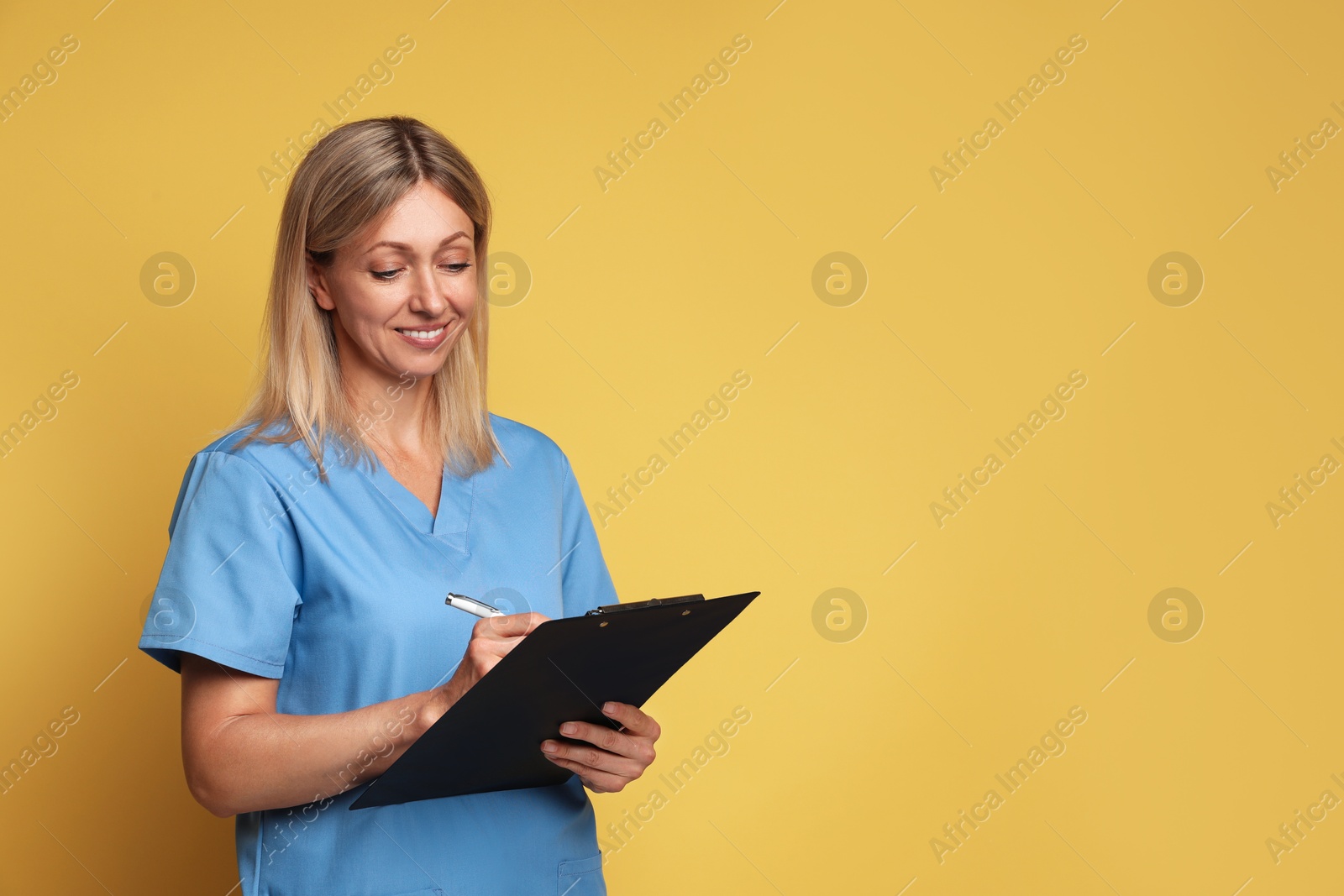 Photo of Portrait of nurse in medical uniform with clipboard on yellow background, space for text