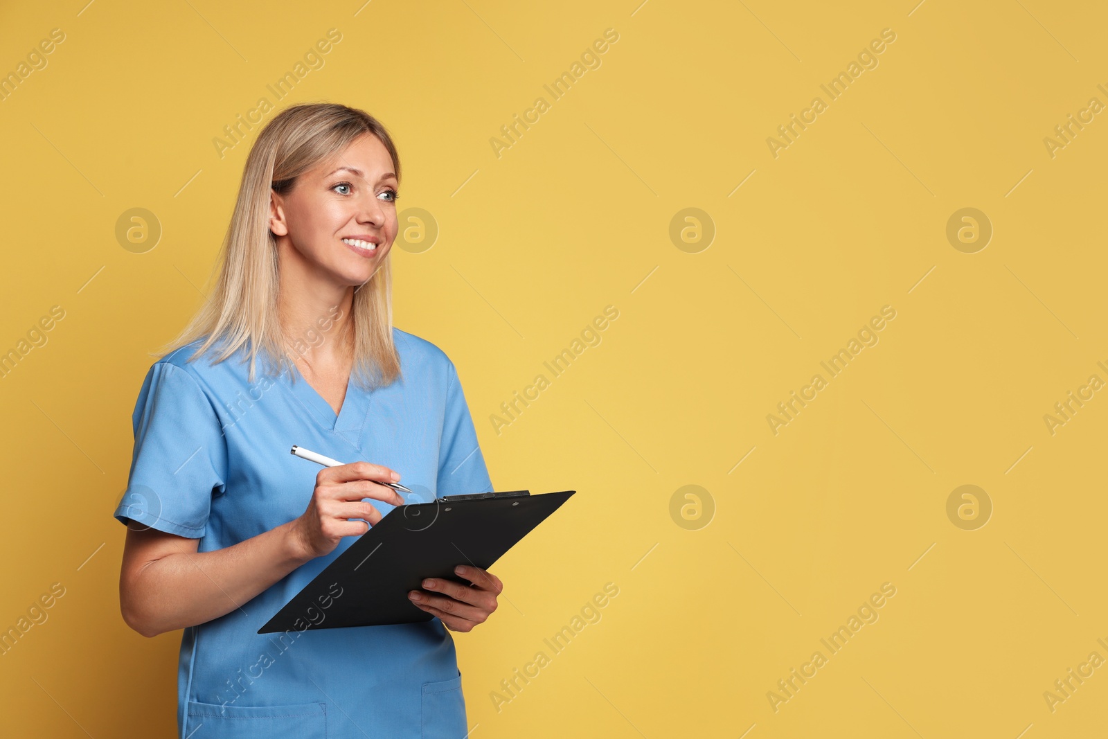 Photo of Portrait of nurse in medical uniform with clipboard on yellow background, space for text