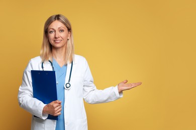 Portrait of doctor in medical uniform with stethoscope and clipboard on yellow background