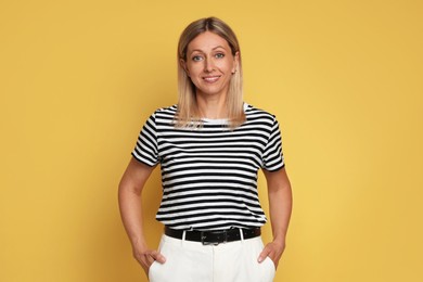 Portrait of beautiful smiling woman on yellow background