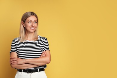 Portrait of beautiful smiling woman on yellow background, space for text