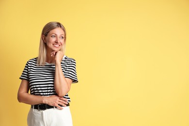 Photo of Portrait of beautiful smiling woman on yellow background, space for text