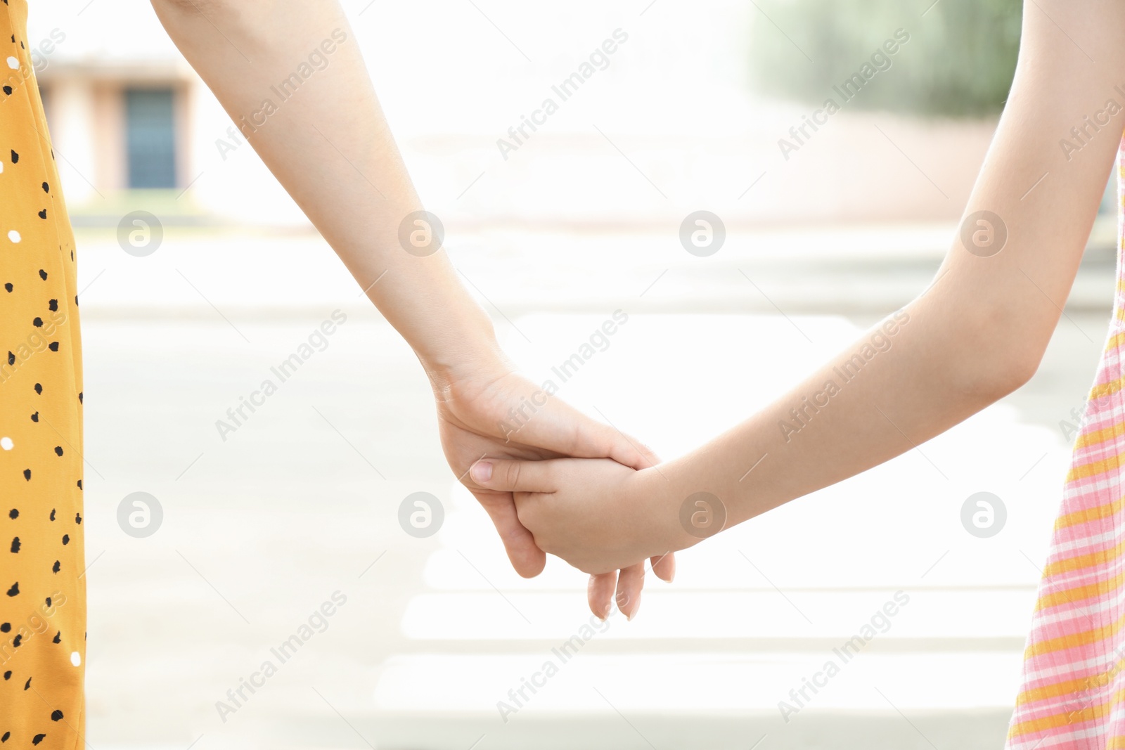 Photo of Mother and daughter holding hands outdoors, closeup