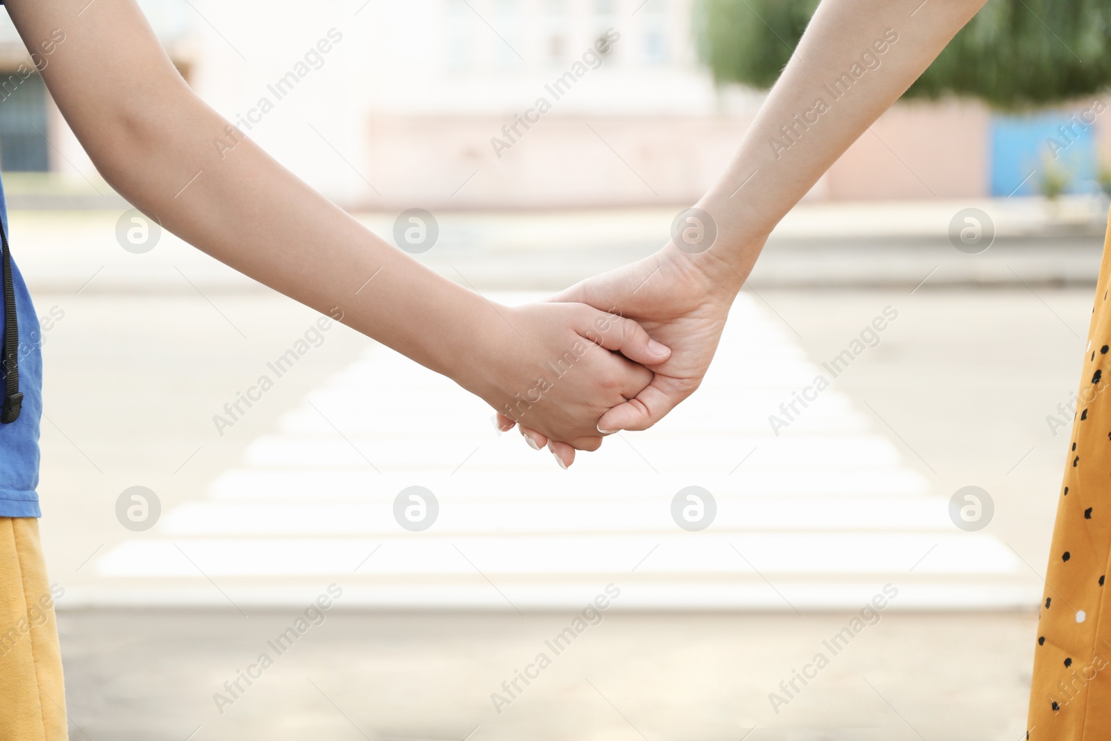 Photo of Mother and daughter holding hands outdoors, closeup