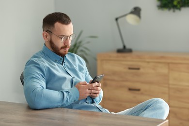 Handsome man looking at smartphone in office