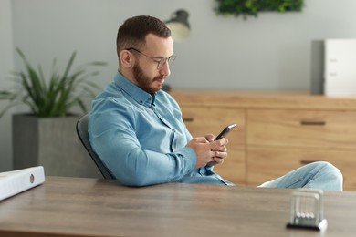 Handsome man looking at smartphone in office