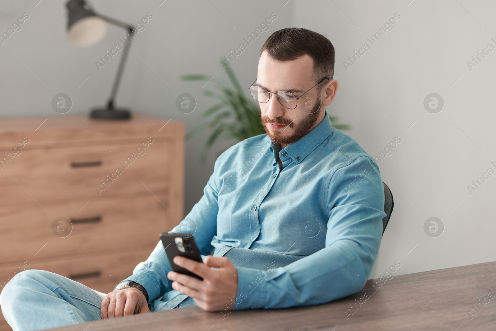 Photo of Handsome man looking at smartphone in office