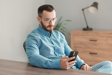 Photo of Handsome man looking at smartphone in office