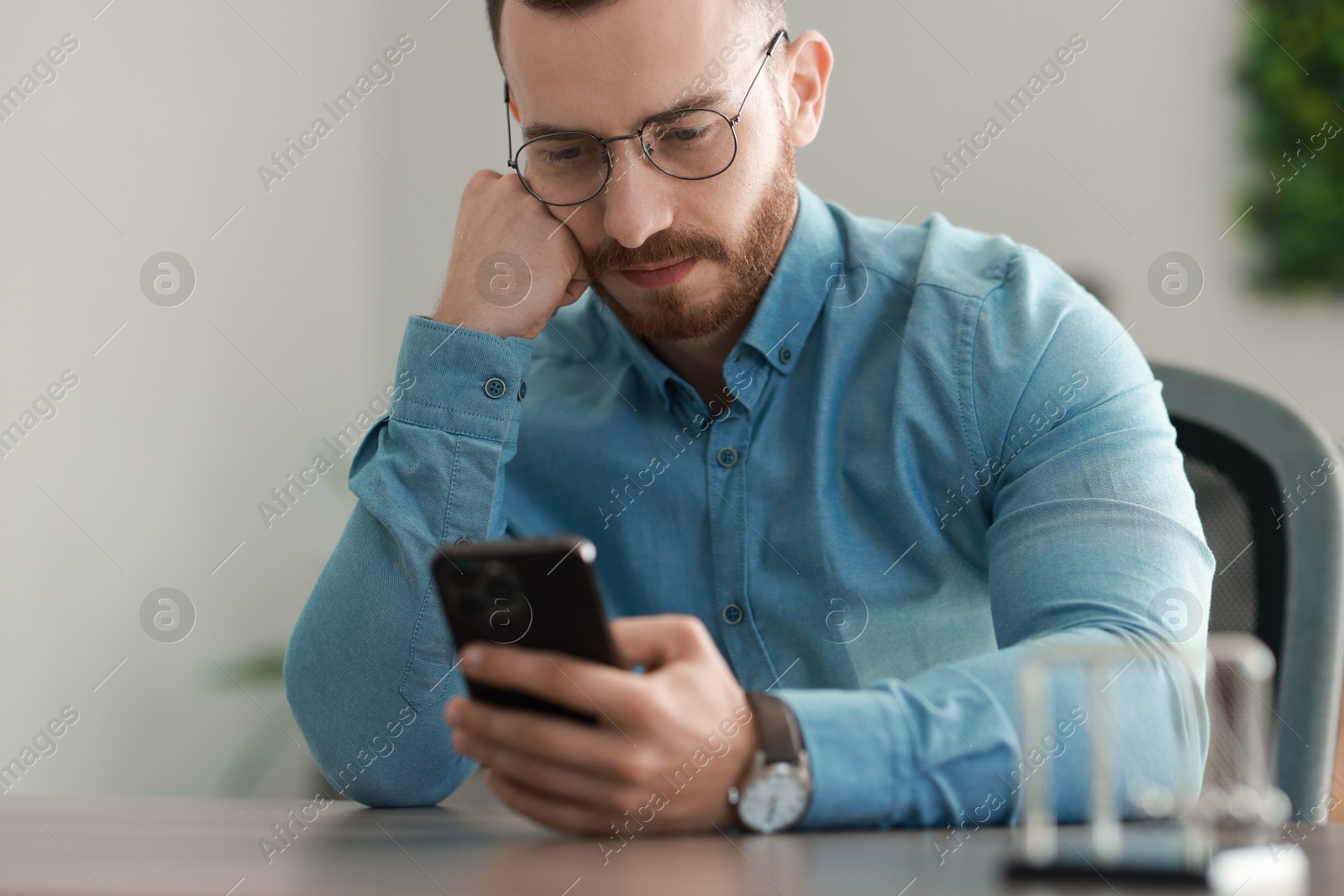 Photo of Handsome man looking at smartphone in office