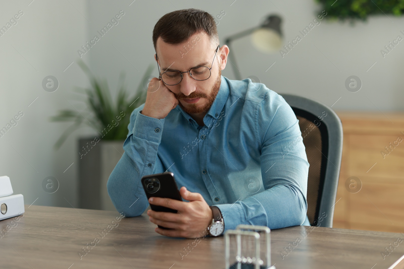 Photo of Handsome man looking at smartphone in office