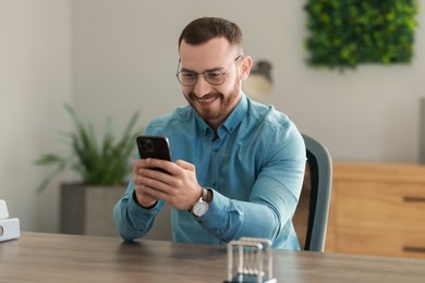 Smiling man looking at smartphone in office