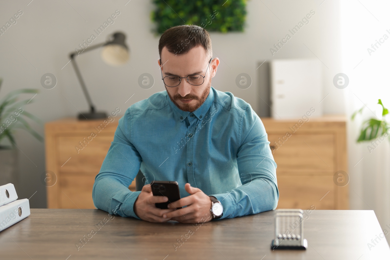 Photo of Handsome man looking at smartphone in office